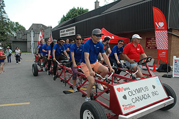 Group of Olympus employees riding a four-wheeled group tandem bike