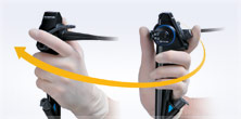 Gloved hand demonstrating range of motion of endoscope controller with arrow superimposed on image